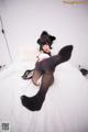 A woman in black stockings is sitting on a bed.