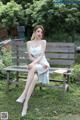 A woman sitting on a wooden bench in a park.