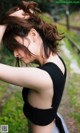 A woman in a black top is standing in the grass.