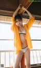 a woman in a yellow jacket and white panties posing for a picture