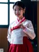 A woman in a red and white hanbok is posing for a picture.