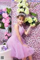 A woman in a pink dress standing in front of a bathtub.