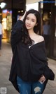 A woman in ripped jeans and a black shirt is posing for a picture.