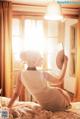 A woman sitting on a bed holding a fan.