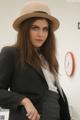 A woman in a suit and hat posing for a picture.