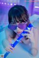 A woman in a pink bikini holding a blue light saber.