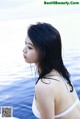 A woman in a white bikini standing in the water.