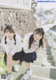 A couple of young women standing next to each other on some steps.