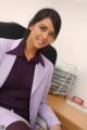 A woman in a purple suit sitting at a desk.