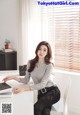 a woman sitting at a desk in front of a window