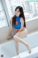 A woman in a superman costume sitting in a bathtub.