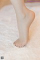 A close up of a woman's bare feet on a white rug.