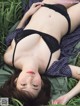 A woman laying in the grass wearing a black lingerie.