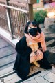 A woman wearing a face mask sitting on the ground.