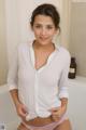 A woman in a white shirt and pink panties posing in a bathtub.