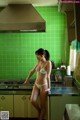 A woman in a white bikini standing in a kitchen.