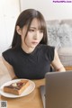 A woman sitting at a table with a plate of toast and a laptop.