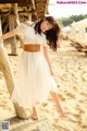 A woman in a white dress standing on a beach.