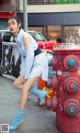 A woman leaning against a red fire hydrant on a city street.