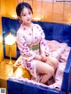 A woman in a kimono sitting on a bathtub.