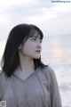 A woman standing on a beach next to the ocean.