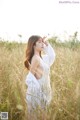 A woman in a white dress standing in a field.