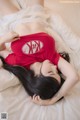 A woman laying on a bed wearing a red shirt.