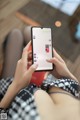 A woman sitting on a couch holding a phone with a message on the screen.