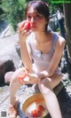 A woman sitting on the ground holding a bowl of tomatoes.