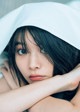 A woman laying on a bed under a white sheet.