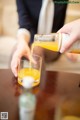 A person pouring orange juice into a glass.