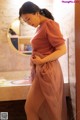 A woman in a pink dress standing in a bathroom.