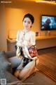 A woman in a kimono sitting on a couch in a hotel room.