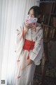 A woman in a white and red kimono holding a fan.