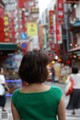 A woman in a green dress is walking down the street.